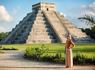  Girl tourist in a hat stands near the pyramid  in Chichen Itza.  Yucatan, Mexico