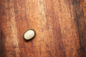biała broszka na drewnianym stole