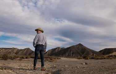 Adult man in cowboy hat standing against mountains in Tabernas desert. Almeria, Spain