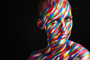 Makeup is an art. Studio shot of a young woman posing with brightly colored paint on her face...