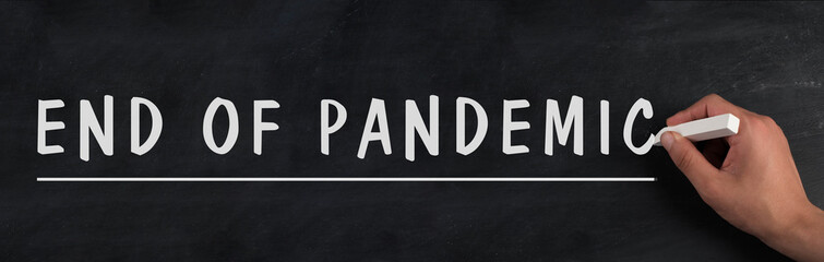 The words end of pandemic are standing on a chalkboard, stop of covid-19 regulations in progress,...