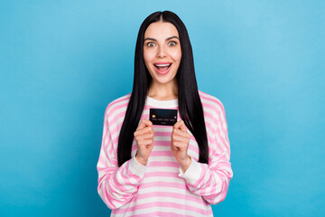 Photo of young excited girl credit card salary income investment advertise isolated over blue color...