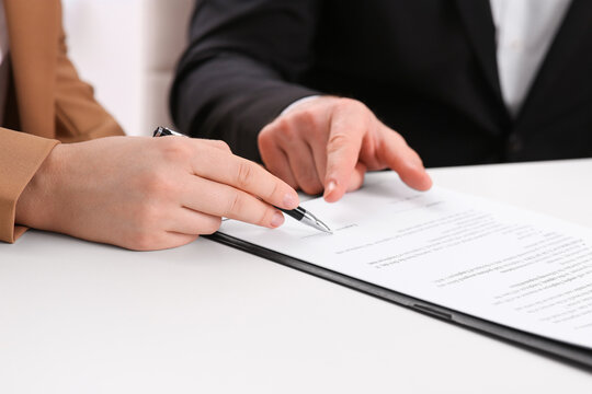 Businesspeople signing contract at white table, closeup of hands