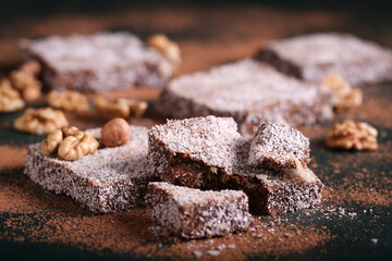 chocolate brownie cake with nuts in coconut chips lies on a wooden table