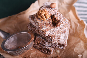chocolate brownie cake with nuts in coconut chips lies on a wooden table