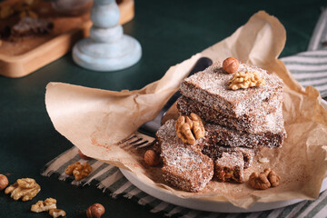 chocolate brownie cake with nuts in coconut chips lies on a wooden table