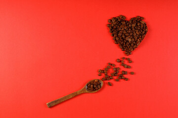 Heart coffee. Roasted coffee beans in the shape of heart on bright red background. Concept of coffee love, Valentines Day, good mood, gift. With wooden spoon.