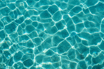Clear water background. Top view of completely transparent turquoise sea water with sun reflections