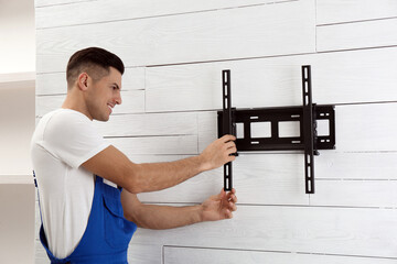 Professional technician installing TV bracket on wall indoors
