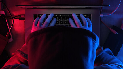 hacker working on laptop at night . hands of a hacker in rubber gloves