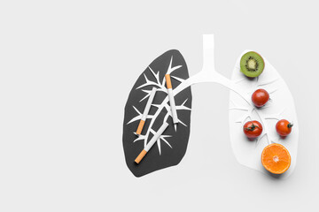 Paper human lungs with healthy products and cigarettes on light background