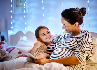 You picked a good one. Cropped shot of an attractive young pregnant woman reading her daughter a...