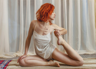 Flexible beautiful young woman is engaged in fitness. Bare legs and shoulders. Red hair. Side view....