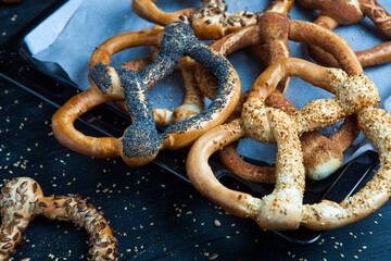Fresh prepared homemade soft pretzels. Different types of baked bagels with seeds on a wood background.