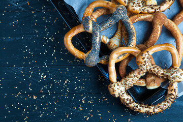 Fresh prepared homemade soft pretzels. Different types of baked bagels with seeds on a wood background.