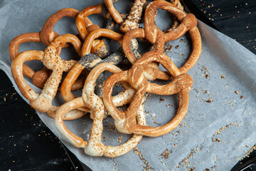 Fresh prepared homemade soft pretzels. Different types of baked bagels with seeds on a wood background.