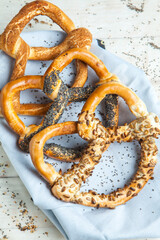 Fresh prepared homemade soft pretzels. Different types of baked bagels with seeds on a wood background.