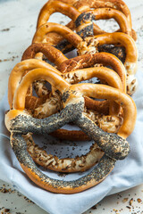 Fresh prepared homemade soft pretzels. Different types of baked bagels with seeds on a wood background.