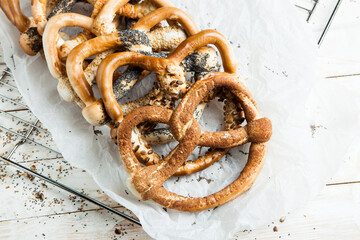 Fresh prepared homemade soft pretzels. Different types of baked bagels with seeds on a wood background.