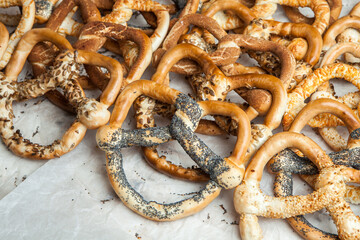 Fresh prepared homemade soft pretzels. Different types of baked bagels with seeds on a wood background.