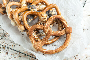 Fresh prepared homemade soft pretzels. Different types of baked bagels with seeds on a wood background.