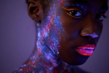 black female with neon make-up body art posing looking at camera, isolated on purple. beautiful female with dark skin with colourful paintings on face, calm and peaceful. fashion, art concept