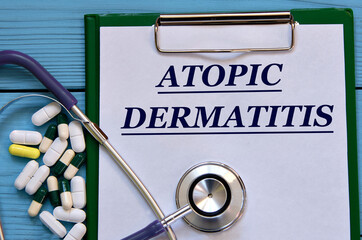 ATOPIC DERMATITIS - word on a white sheet on a blue background with tablets and a stethostecop