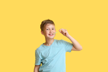 Little boy in blue t-shirt chewing gum on yellow background - obrazy, fototapety, plakaty