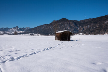 Stadl und Spuren  im Schnee mit bergen im Hintergrund