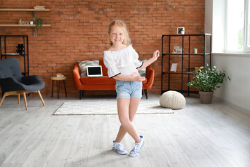 Little redhead girl in blouse dancing at home