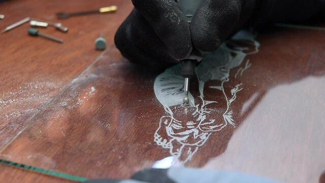 A craftsman does glass engraving with a rotary tool
