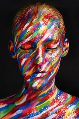 Beauty embraces every color. Studio shot of a young woman posing with brightly colored paint on her face against a black background.