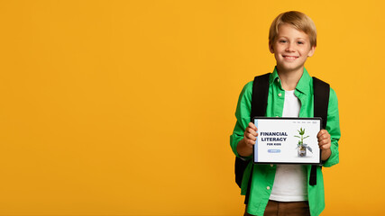 Cheerful boy demonstrating tablet computer with Financial Literacy For Kids online school website...
