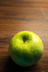 Einzelner grüner Apfel auf rustikalem Holztisch