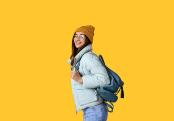 Pretty young woman in warm clothes on color background