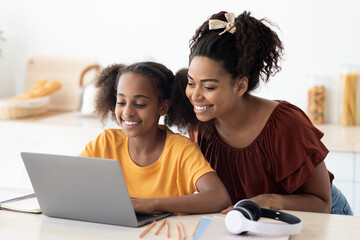 Cute black mother and kid using laptop together, closeup photo
