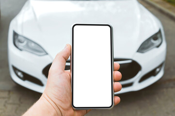 Smartphone mockup in the hands of a man. Against the background of a white electric car.
