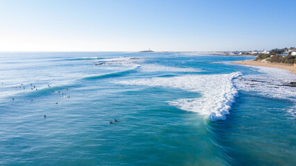 Aerial view of surfers riding waves in Spain. Atlantic surf at Trafalgar drone view