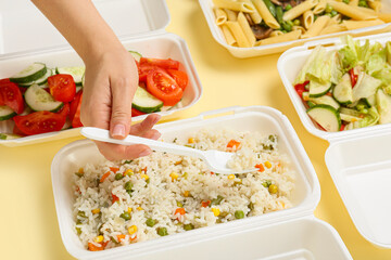 Woman taking food from container on color background, closeup