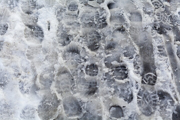 slippery sidewalk in winter covered with slush full of footprints