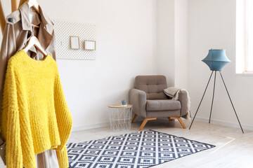 Interior of light living room with soft armchair, table and standing lamp