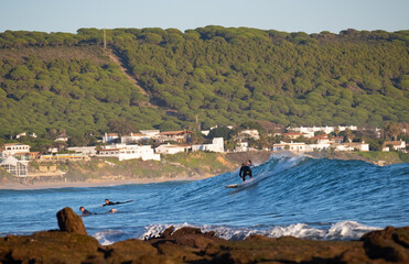 Young surfer riding perfect surf wave at the beach of Caños de Meca. Spanish Atlantic coast in...