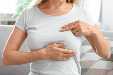 Mature woman feeling discomfort in her breast at home. Cancer awareness concept