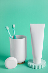 Tube with toothpaste, dental floss and holder with toothbrushes on color background