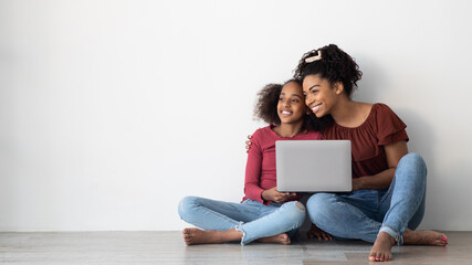 Happy black mom and teen kid using laptop, copy space