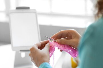 Young African-American woman taking online knitting classes at home, closeup