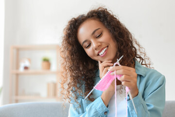 Young African-American woman knitting at home