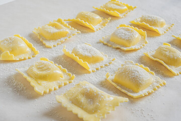 Fresh ravioli pasta durind cooking on light background