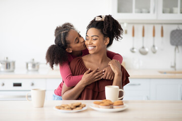 Cute black girl kissing her mom after breakfast