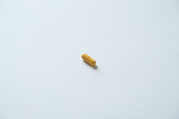 a yellow  medical pill on a white background with 